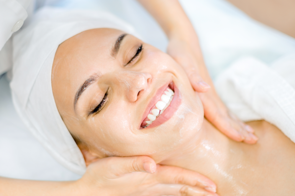 Smiling woman receiving a glass skin facial session.